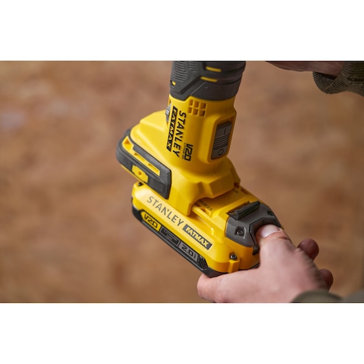 Stanley SFMCE500B cordless drill close-up showing yellow V20 FATMAX battery being inserted.