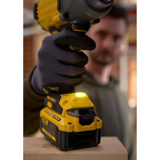 Photo of STANLEY SFMCF940M1 impact driver in use, yellow and black design, close-up of gloved hand.