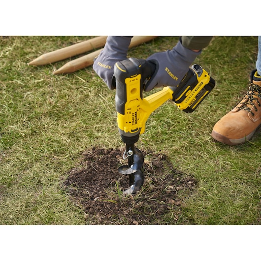 STANLEY SFMCGA75M1 cordless garden auger drilling into soil, close-up outdoor scene.