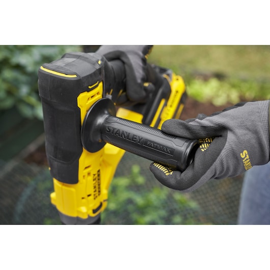 Photo of STANLEY SFMCGA75M1 yellow and black power tool handle held by gloved hands, outdoor setting.