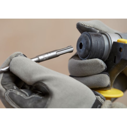 STANLEY SFMCH900M22 rotary hammer close-up with gloved hands inserting a drill bit, product photography.