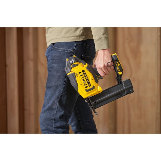 Photo of STANLEY SFMCN618B-XJ cordless yellow nail gun, held in hand, shown in side view.