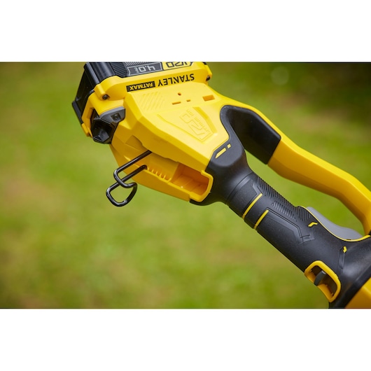 Photo of STANLEY SFMCPS620M1 chainsaw handle with black and yellow ergonomic grip, side outdoor view.