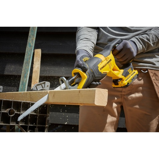 STANLEY SFMCS300B cordless reciprocating saw in use cutting wood, close-up view of power tool.