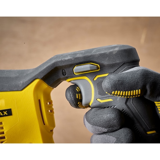 STANLEY SFMCS300B power tool close-up, showing yellow and black ergonomic handle with gloved hand pulling trigger.