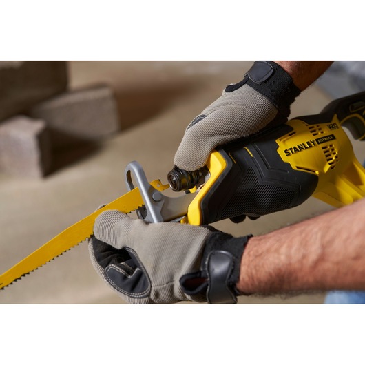 STANLEY SFMCS300B reciprocating saw held by gloved hands, yellow and black close-up side view.