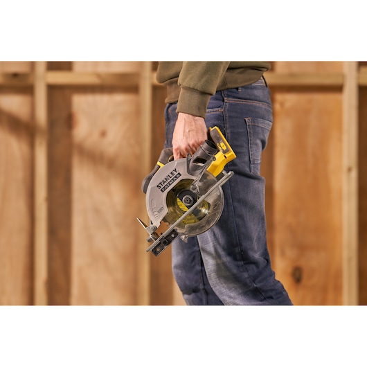 Stanley SFMCS500B cordless circular saw held by person, shown in a workshop setting.