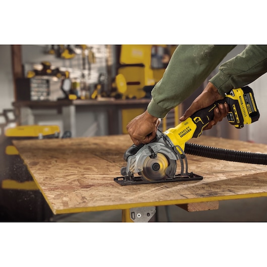 STANLEY SFMCS515B cordless circular saw in use cutting plywood, close-up in workshop setting.