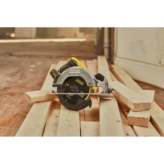 STANLEY SFMCS550B circular saw on planks, brushless model, black and yellow color, workshop setting.