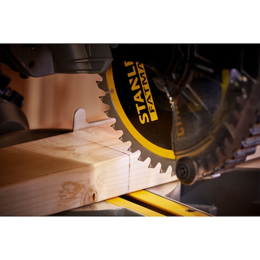 STANLEY SFMCS701M1 miter saw close-up cutting wood, black and yellow blade, woodworking context.