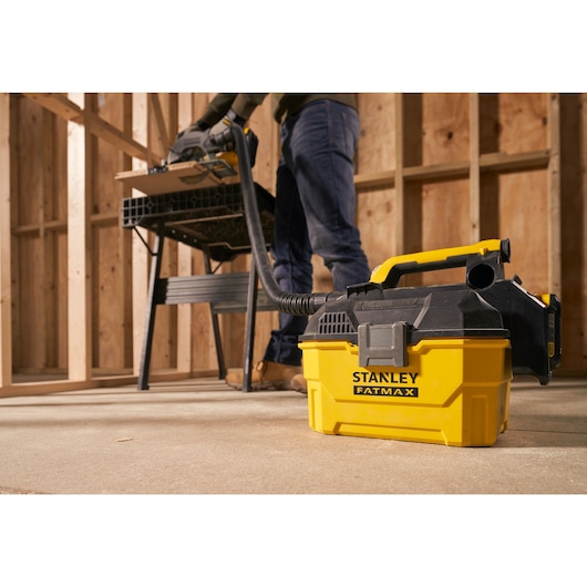 STANLEY SFMCV002B portable yellow and black vacuum in workshop setting, connected to tool.