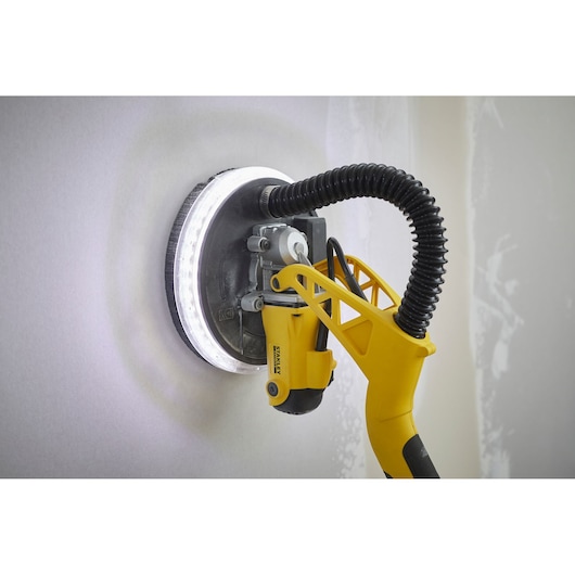 STANLEY SFMEE500S drywall sander with LED ring light sanding a wall, side view.
