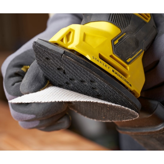 Photo of STANLEY SFMEW210S sander close-up with sanding pad being attached, yellow and black design.
