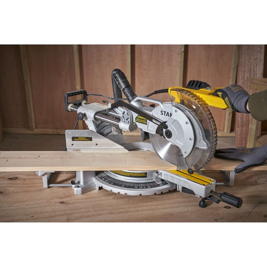 Photo of STANLEY SM1800 miter saw cutting wood, close-up view in workshop setting.