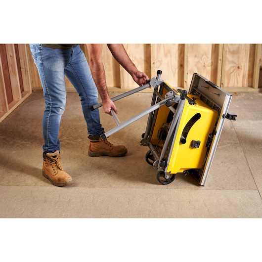 STANLEY SST1800 yellow table saw with folding stand, side angle, being set up in workshop.