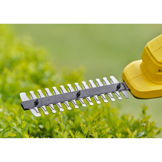 STANLEY STCSS20B hedge trimmer blade close-up outdoors with green foliage background.