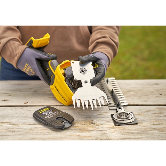 STANLEY STCSS20B garden tool with metal blade attachment and battery on wooden table, close-up.