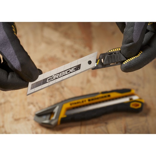 STANLEY STHT0-11818 utility knife blade being inserted into yellow and black utility knife, close-up view.