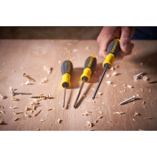 STANLEY STHT0-60335 screwdriver set with black and yellow handles on wood with screws and shavings.