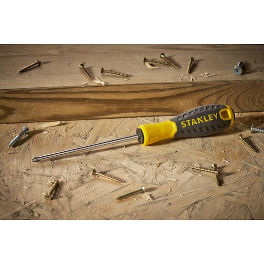 STANLEY STHT0-60335 yellow and black Phillips screwdriver on wood surface with scattered screws.