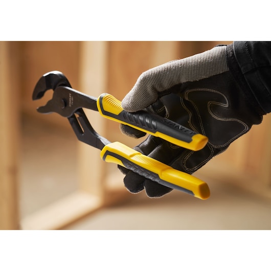 STANLEY STHT0-74361 water pump pliers with yellow and black handles in a gloved hand, close-up.