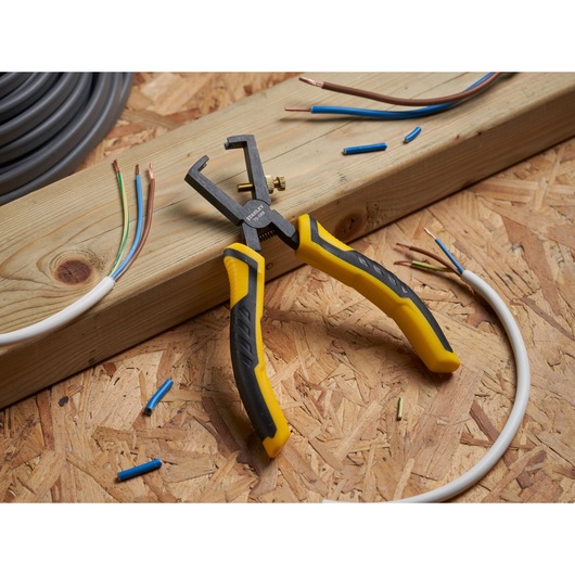 Photo of STANLEY STHT0-75068 wire stripper with black and yellow handles, shown stripping electrical wires.