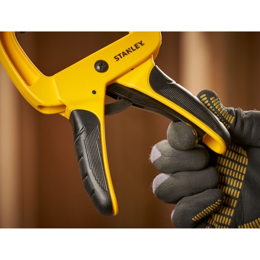STANLEY STHT0-83199 photography of yellow and black clamp handle held by gloved hand, close-up angle.