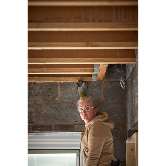 Photo of STANLEY STHT1-77409 laser distance measurer in use on exposed ceiling beams at construction site.