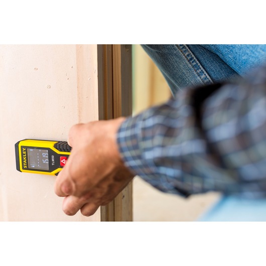 Stanley STHT1-77409 laser distance measurer in use against a wall, close-up view, Photography category.