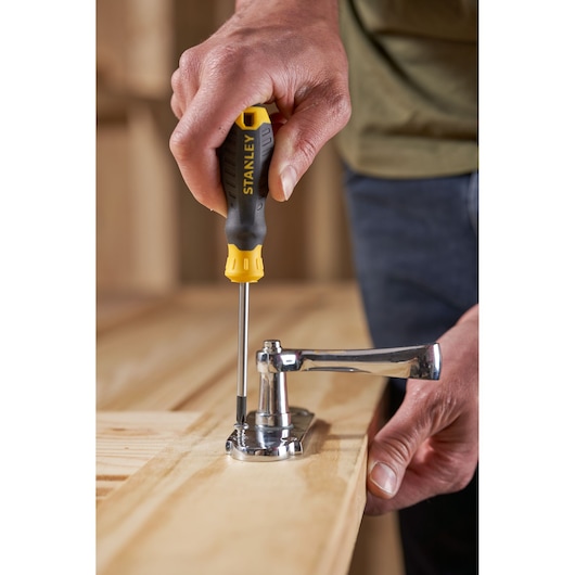 Stanley STHT16155-0 screwdriver used to fasten a door handle onto a wooden surface.