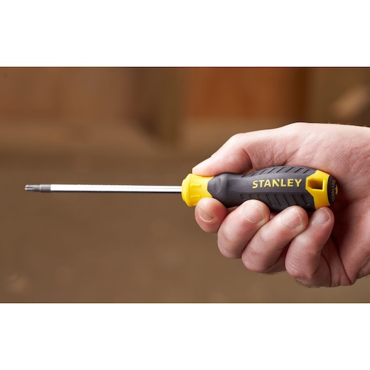 Stanley STHT16179-0 screwdriver with yellow and black ergonomic handle, shown held in a hand.