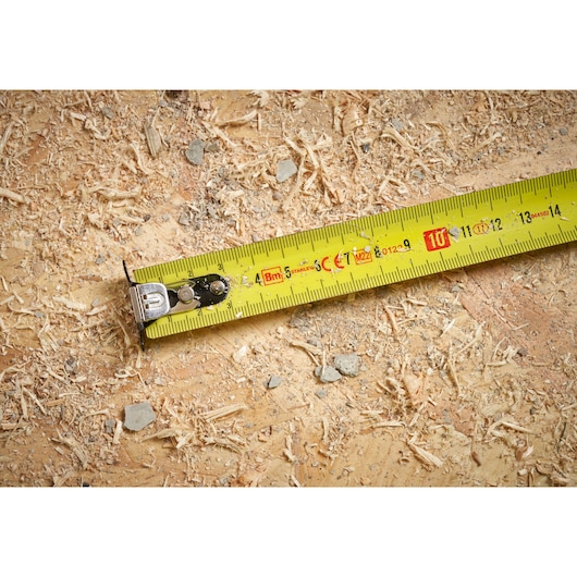 STANLEY STHT37232 tape measure photography showing yellow blade on sawdust surface.