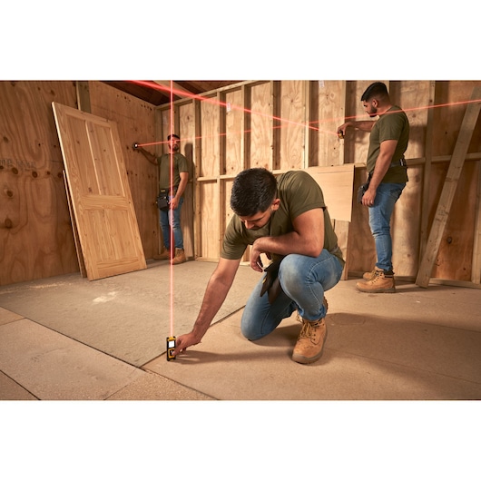 STANLEY STHT77100-0 laser level in use on construction site by workers, projecting red alignment lines.