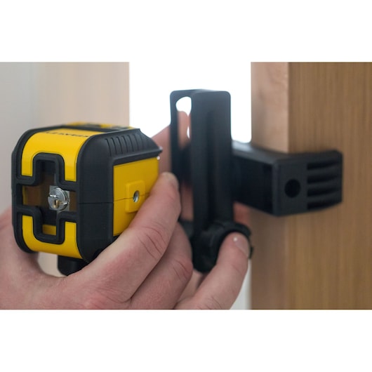 STANLEY STHT77499-1 yellow and black laser level in use, clamped to wooden surface, photography close-up.