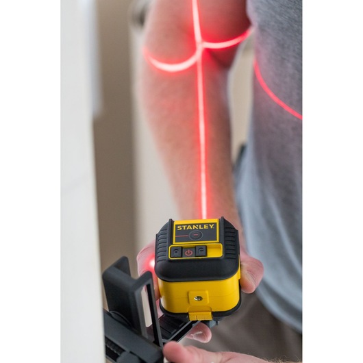 STANLEY STHT77502-1 yellow and black cross line laser level in use projecting red laser lines.