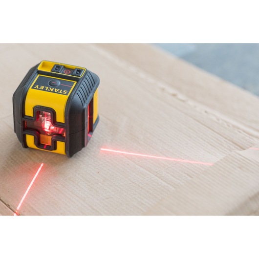 Photo of STANLEY STHT77502-1 laser level projecting red lines on a cardboard surface.