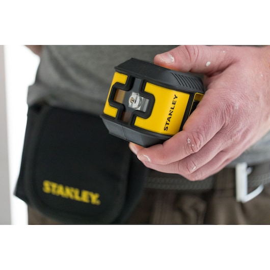 STANLEY STHT77649-1 yellow and black laser level held in hand, pouch visible, close-up photo.