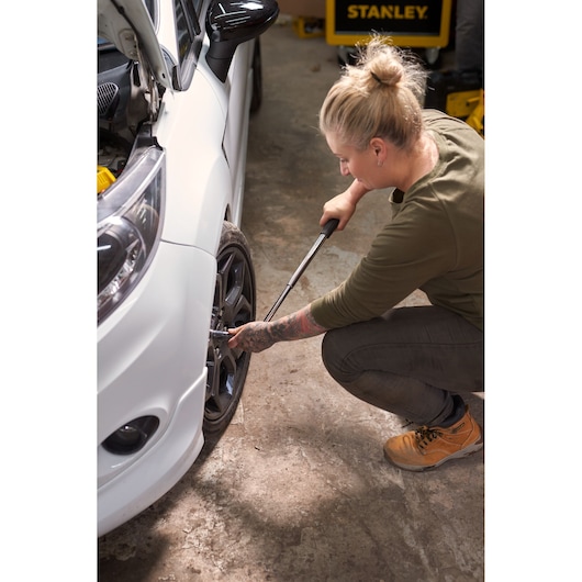 Photo of STANLEY STHT80890-0 torque wrench in use, tightening bolts on a car wheel in a garage.