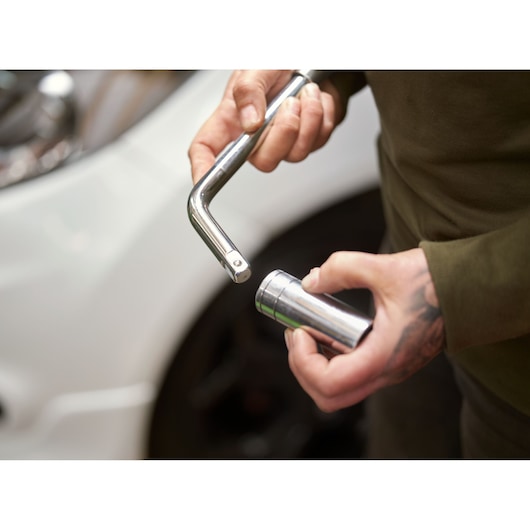 STANLEY STHT80890-0 socket wrench and socket tool held in hand near car, side angle.