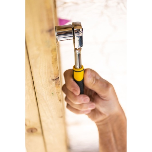 STANLEY STMT82664-0 ratchet wrench with yellow and black handle in use, close-up view.