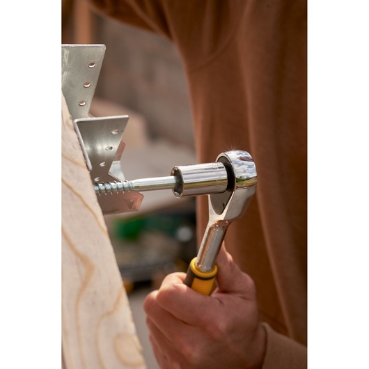 STANLEY STMT82665-0 ratchet tool in use, close-up side view, silver and yellow handle, fastening a screw.