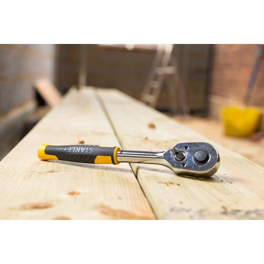 STANLEY STMT82665-0 ratchet wrench with black and yellow handle on wooden planks, angled view.