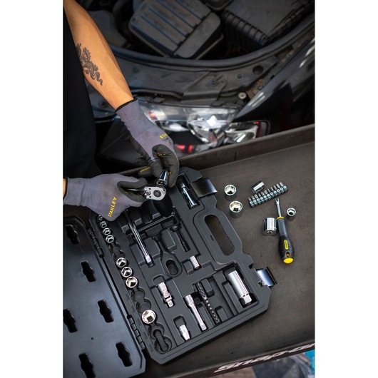 STANLEY STMT82829-1 socket set with ratchet and screwdriver, displayed open by mechanic near car engine.