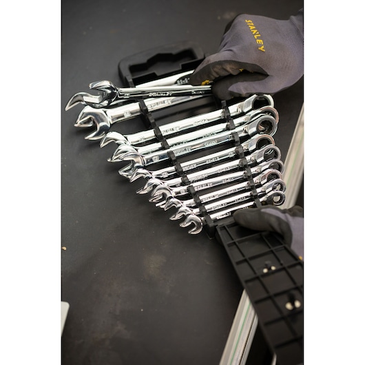 STANLEY STMT82847-0 ratcheting wrench set in holder, chrome finish, shown with gloved hands on black surface.