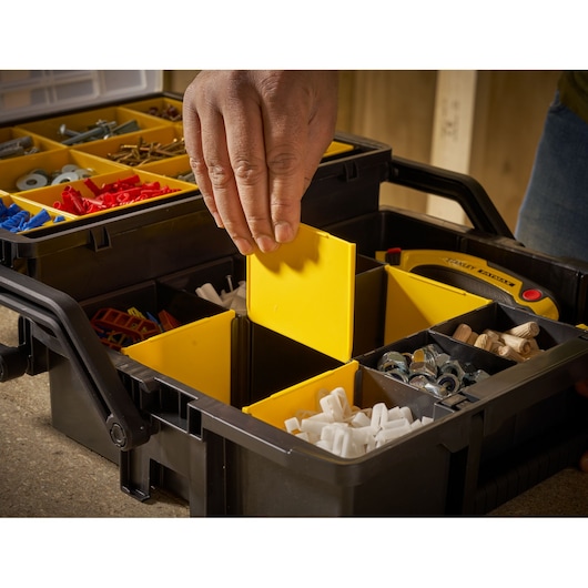 STANLEY STST1-75540 organizer box with yellow compartments, hand adjusting divider, close-up angle.