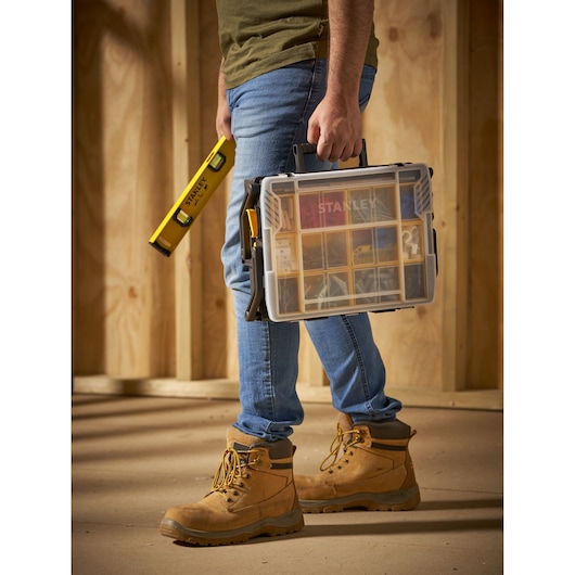 STANLEY STST1-75540 plastic organizer with clear lid and black handle, carried by a person wearing work boots.