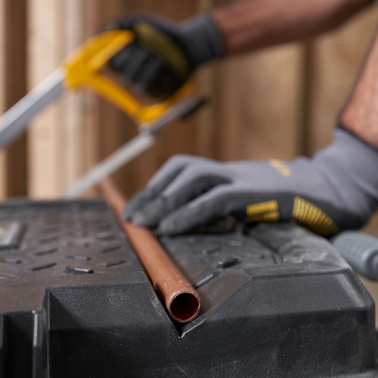 STANLEY STST33090-1 workbench top with gloves and copper pipe, close-up angle.