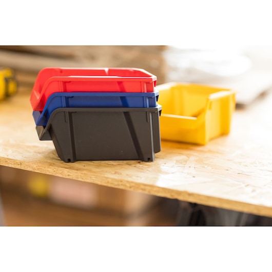 STANLEY STST82736-1 stackable plastic storage bins in red, blue, black and yellow on a wooden surface.