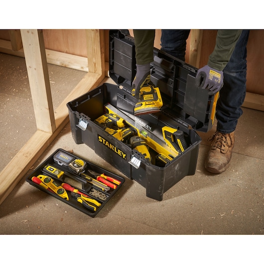 STANLEY STST82976-1 toolbox filled with hand tools and power tools, open on workshop floor, angled top view.