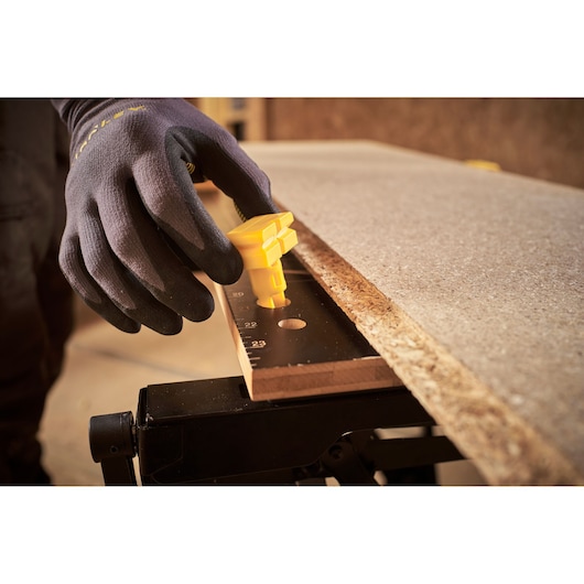 STANLEY STST83400-1 photography of gloved hand adjusting yellow clamp on workbench with wood board.